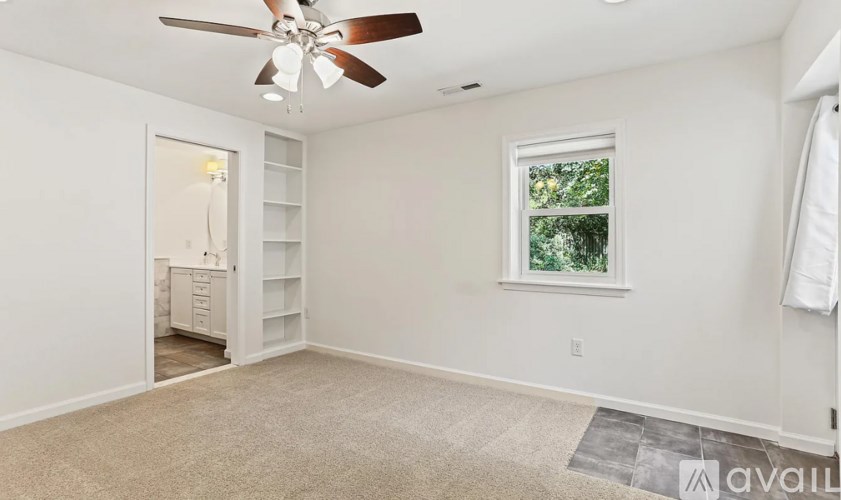 A room with a ceiling fan, a window, and a carpeted floor.