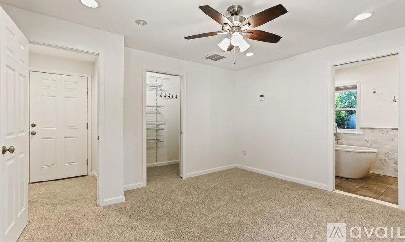 A white bathroom with a fan and a toilet.
