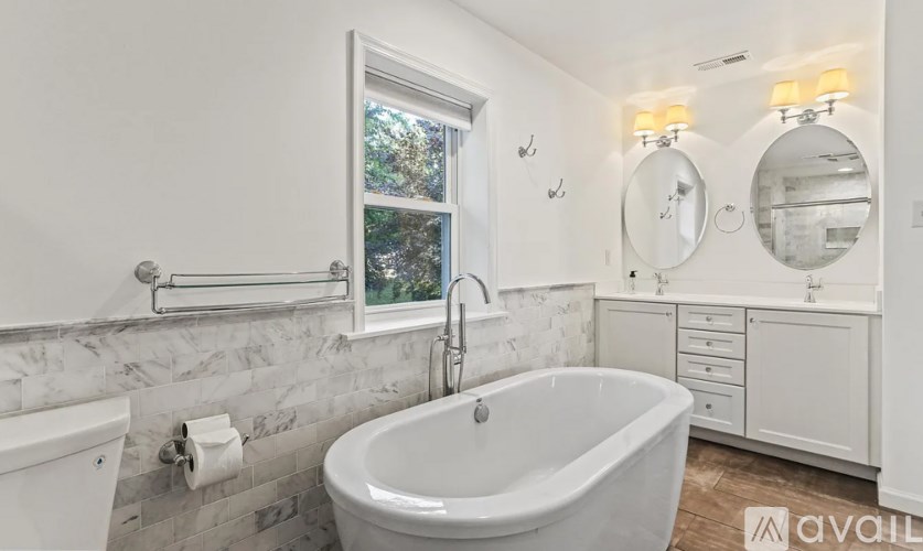 A white bathroom with a tub, sink, and mirror.