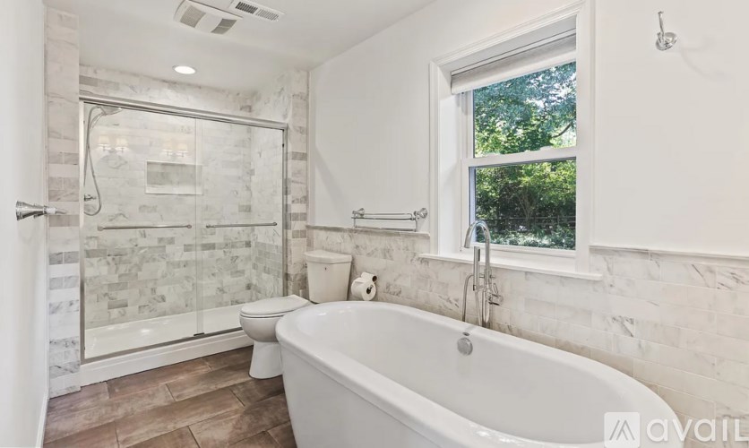 A bathroom with a tub, toilet, and walk-in shower.