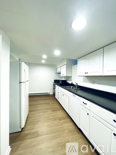 A kitchen with white cabinets and a wooden floor.