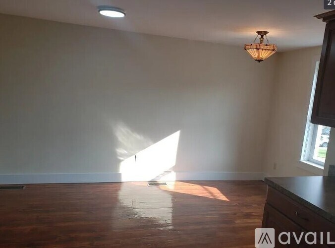 A room with wooden floors and a chandelier hanging from the ceiling.