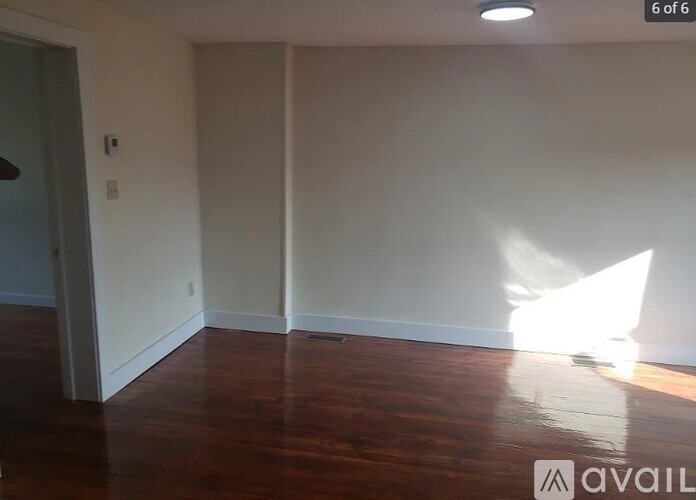 A room with wooden flooring and white walls.