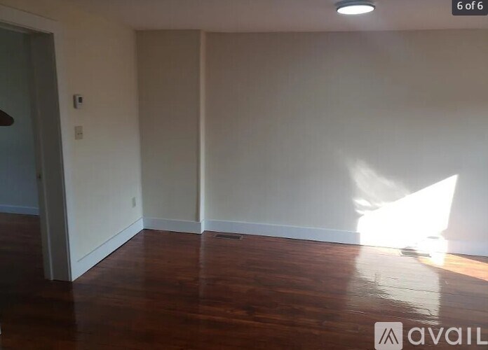 A room with wooden flooring and white walls.