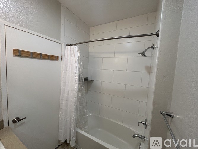 A white bathroom with a white tub and a white shower curtain.