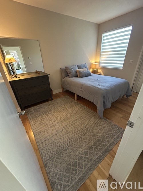 A bedroom with a bed, dresser, and window.