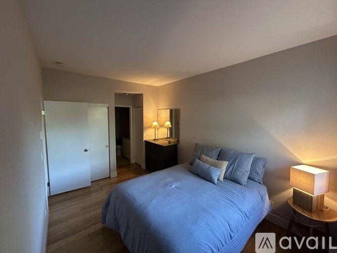 A bedroom with a bed, nightstand, and lamp.