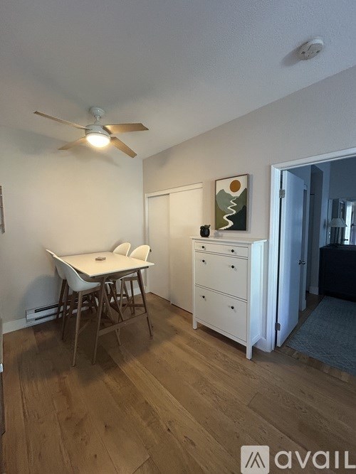 A room with a white table and chairs and a painting on the wall.