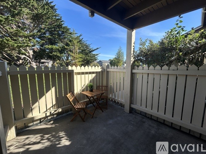 A patio with a table and chairs is surrounded by a white fence.