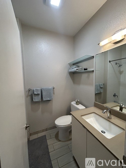 A bathroom with a toilet, sink, mirror and towel rack.