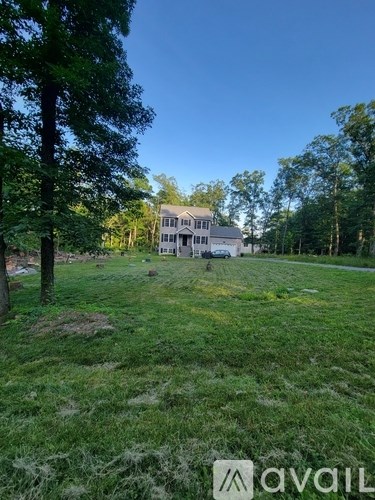 A house is situated in a grassy field with trees around it.