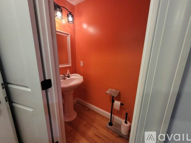 A bathroom with orange walls and a white pedestal sink.