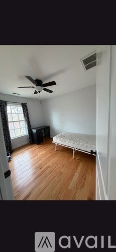 A room with a bed, a fan, and a window.