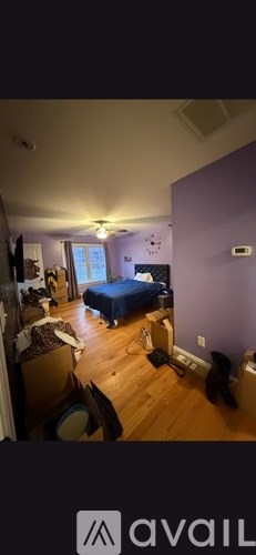 A bedroom with a bed, chair, and a ceiling fan.