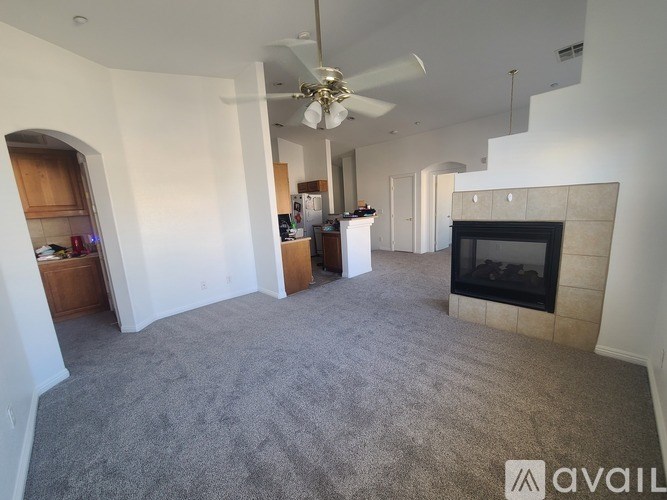 A spacious living room with a fireplace and a ceiling fan.