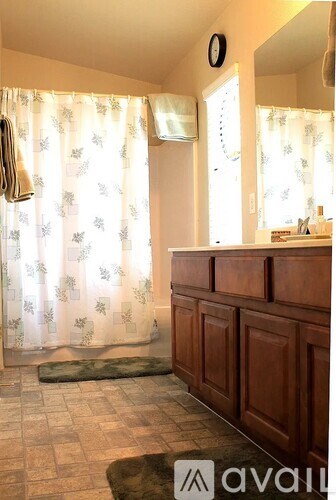 A bathroom with a wooden cabinet and a shower curtain.