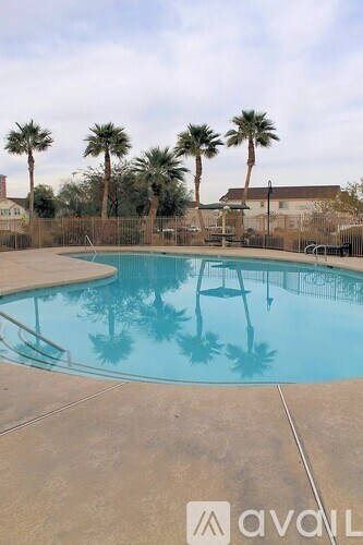 A pool surrounded by palm trees and a fence.