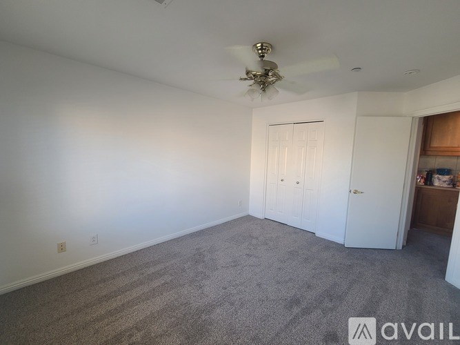 A room with a ceiling fan and carpeted floor.
