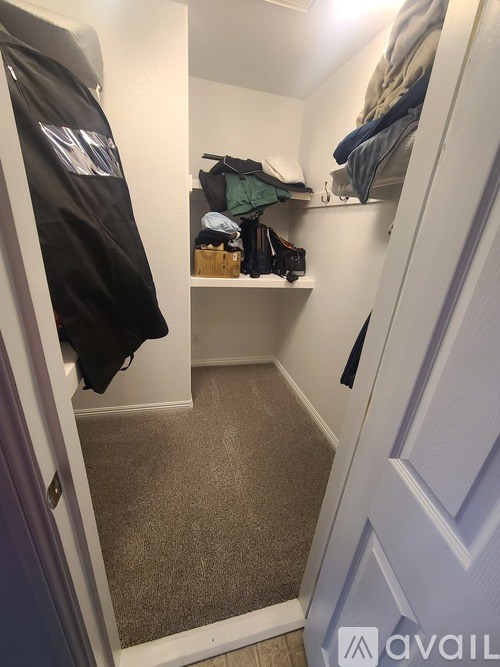 A hallway with a coat hanging on the wall and a shelf with shoes.