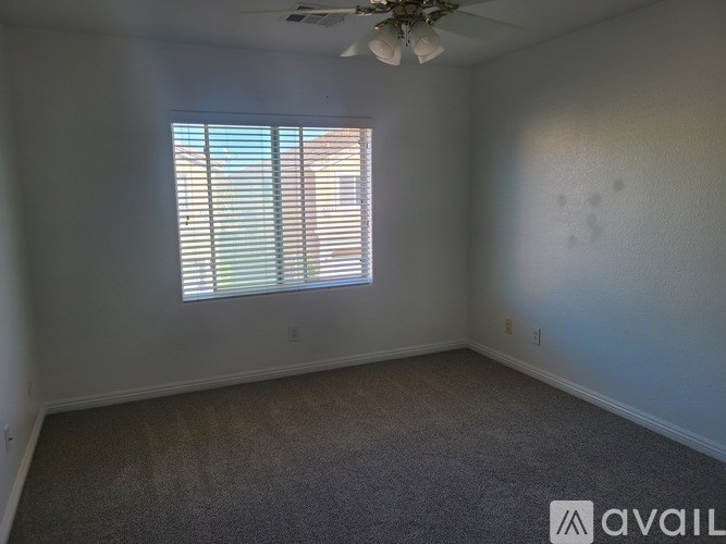A room with a window covered by blinds and a ceiling fan.