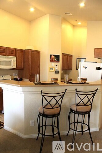 A kitchen with a white island and two chairs.