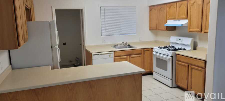 A kitchen with a white stove and wooden cabinets.