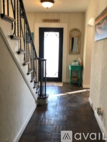 A hallway with a wooden floor and a black metal railing.