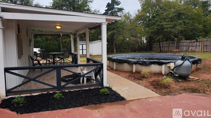 A covered patio area with a hot tub and a grill.