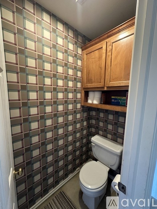 A small bathroom with a toilet and a tiled wall.