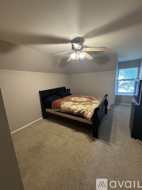 A bedroom with a bed, carpet, and a ceiling fan.