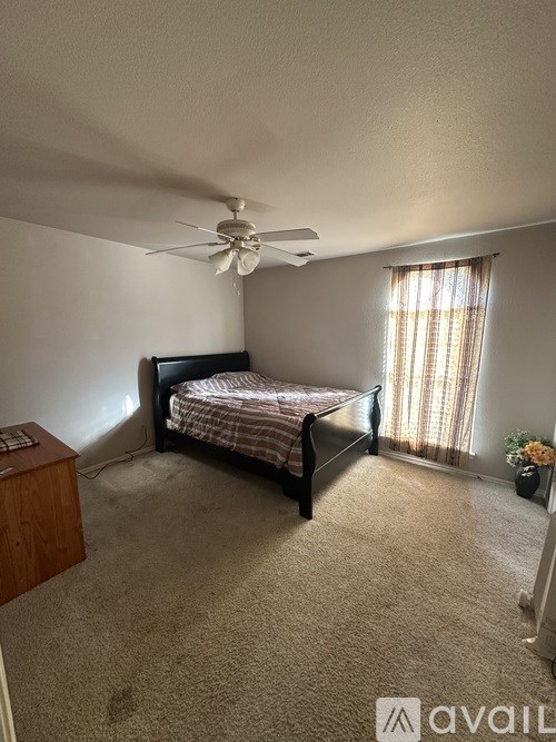 A bedroom with a bed, dresser, and window.
