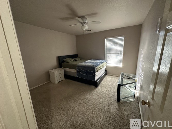 A bedroom with a bed, nightstand, and window.