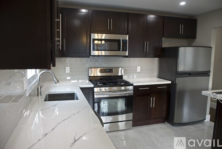 A modern kitchen with dark brown cabinets and stainless steel appliances.