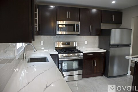A modern kitchen with dark brown cabinets and stainless steel appliances.
