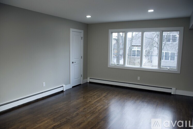 A room with a door, window, and wooden floor.