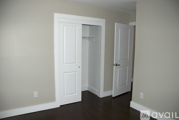 A room with two white doors and a wooden floor.