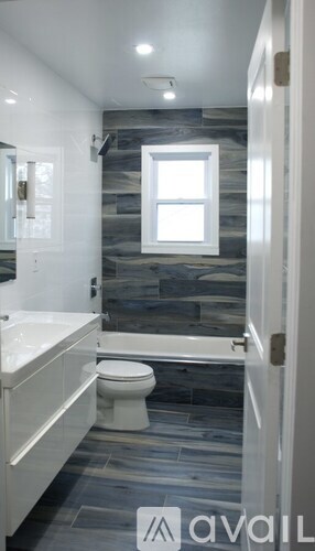 A bathroom with a toilet, sink, and a window.