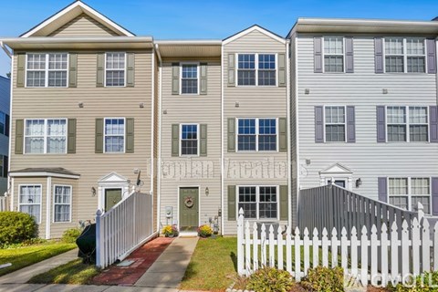 A row of townhouses with white picket fences in front.