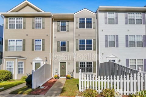 A row of townhouses with white picket fences in front.