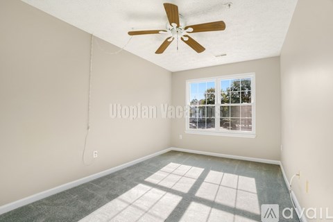 A room with a ceiling fan and a window letting in sunlight.