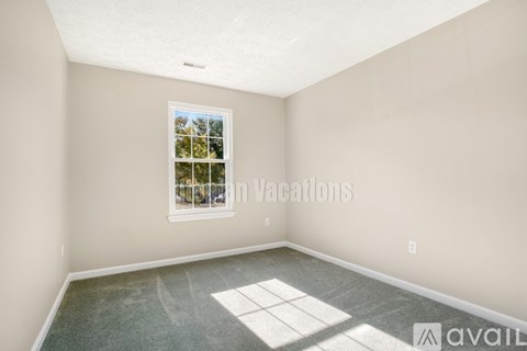 A room with a window showing a view of trees and a car.