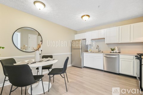 A kitchen with a table and chairs in the foreground and a fridge and cabinets in the background.