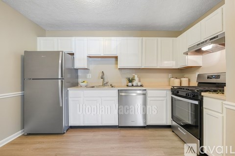 A kitchen with white cabinets and a stainless steel refrigerator.