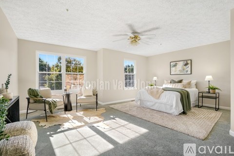 A bedroom with a large bed, a chair, and a rug.