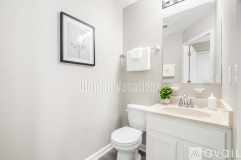 A white bathroom with a toilet, sink, and mirror.