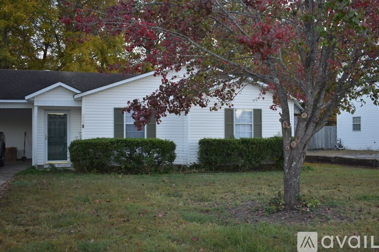 A white house with a tree in front of it.