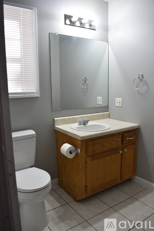 A bathroom with a toilet, sink, and mirror.