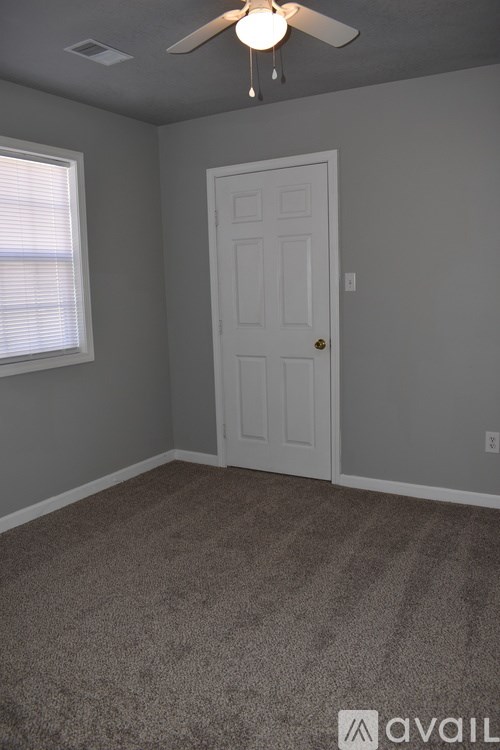 A room with a white door and a ceiling fan.