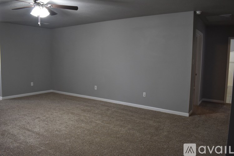 A room with a ceiling fan and carpeted floor.