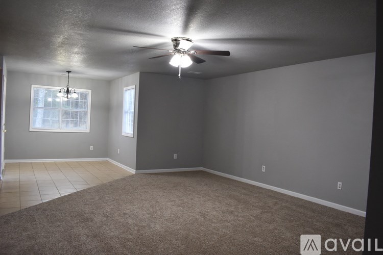 A room with a carpeted floor, a ceiling fan, and a window.